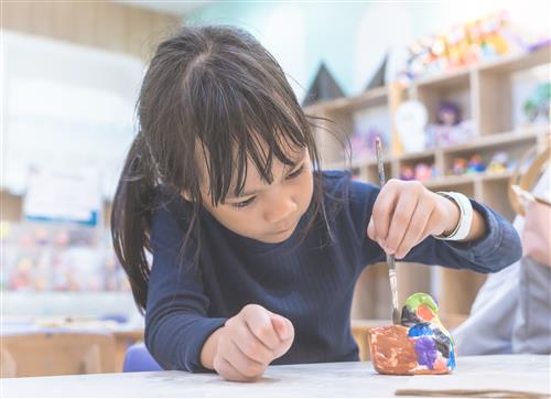 Girls painting clay 
